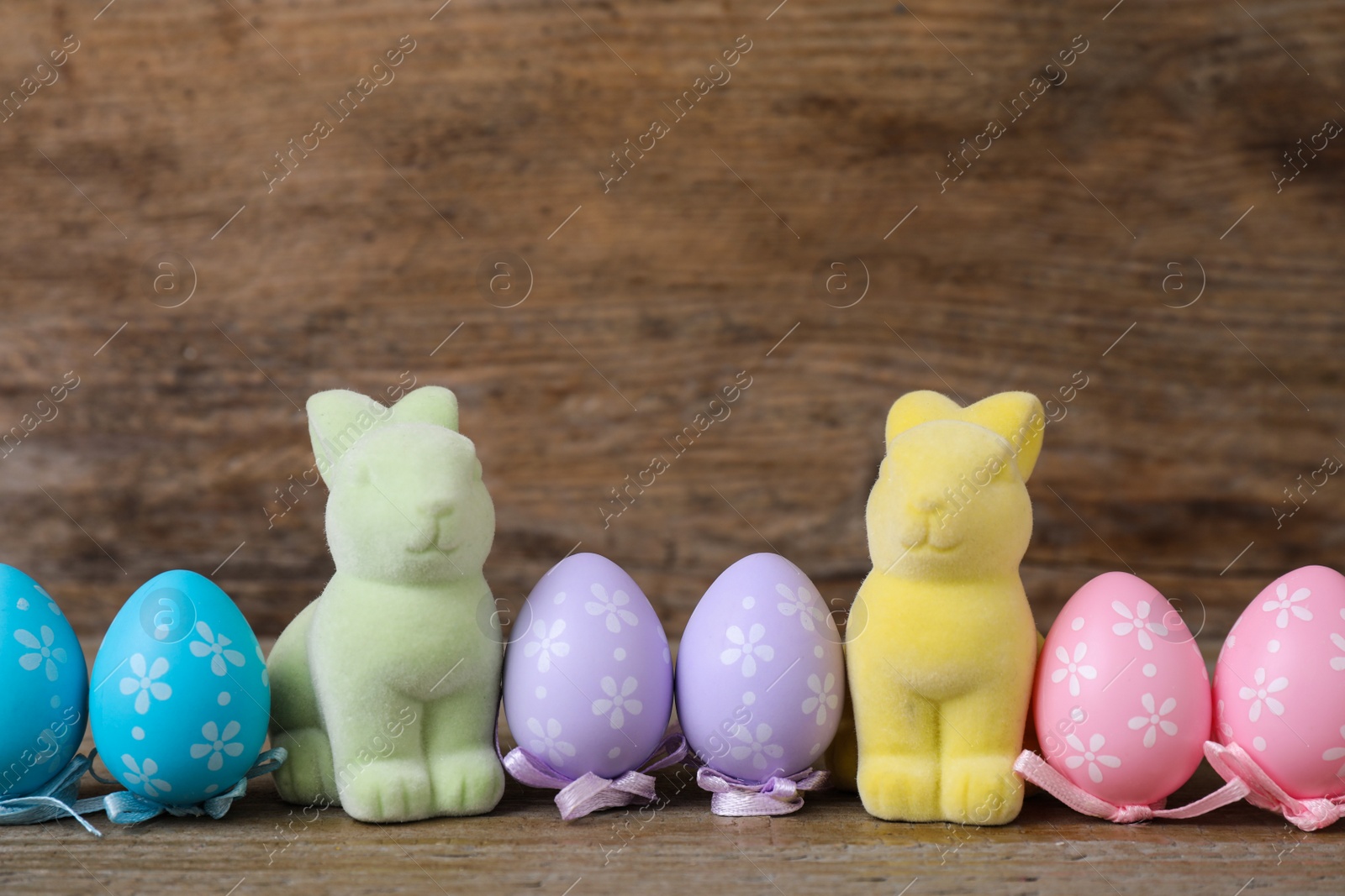 Photo of Easter bunnies and painted eggs on wooden background