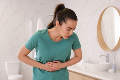 Young woman suffering from stomach ache in bathroom. Food poisoning