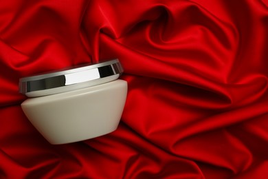 Photo of Jar of hair care cosmetic product on red fabric, top view. Space for text
