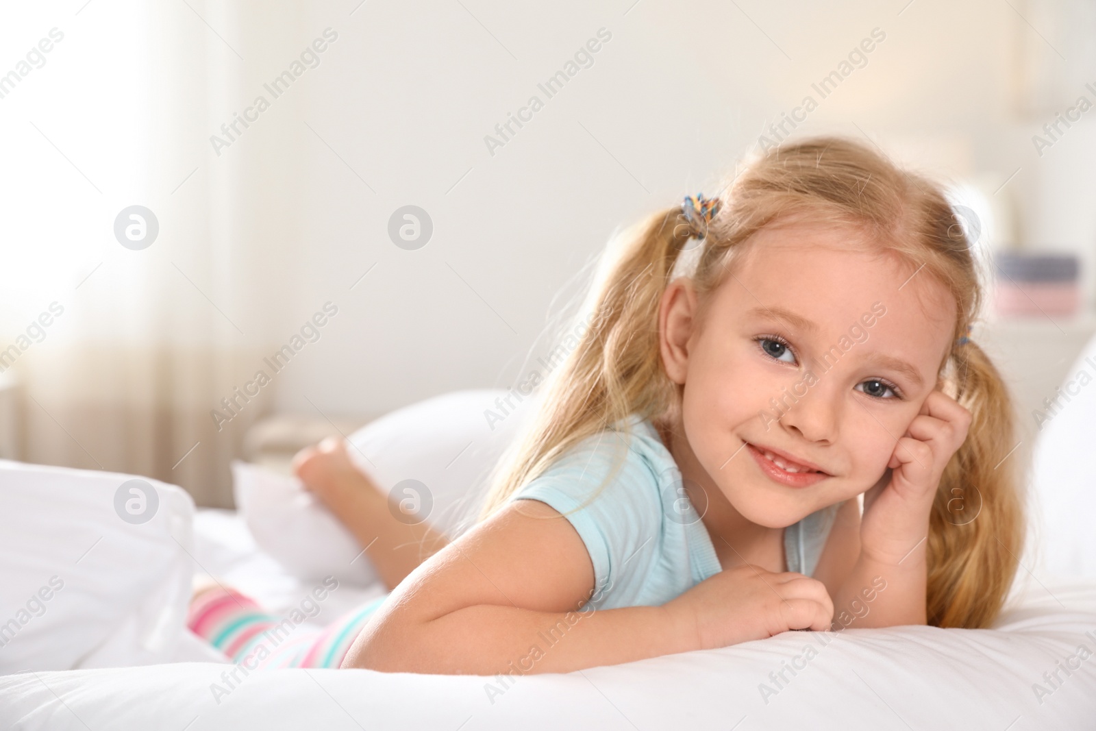 Photo of Portrait of cute little girl resting on large bed