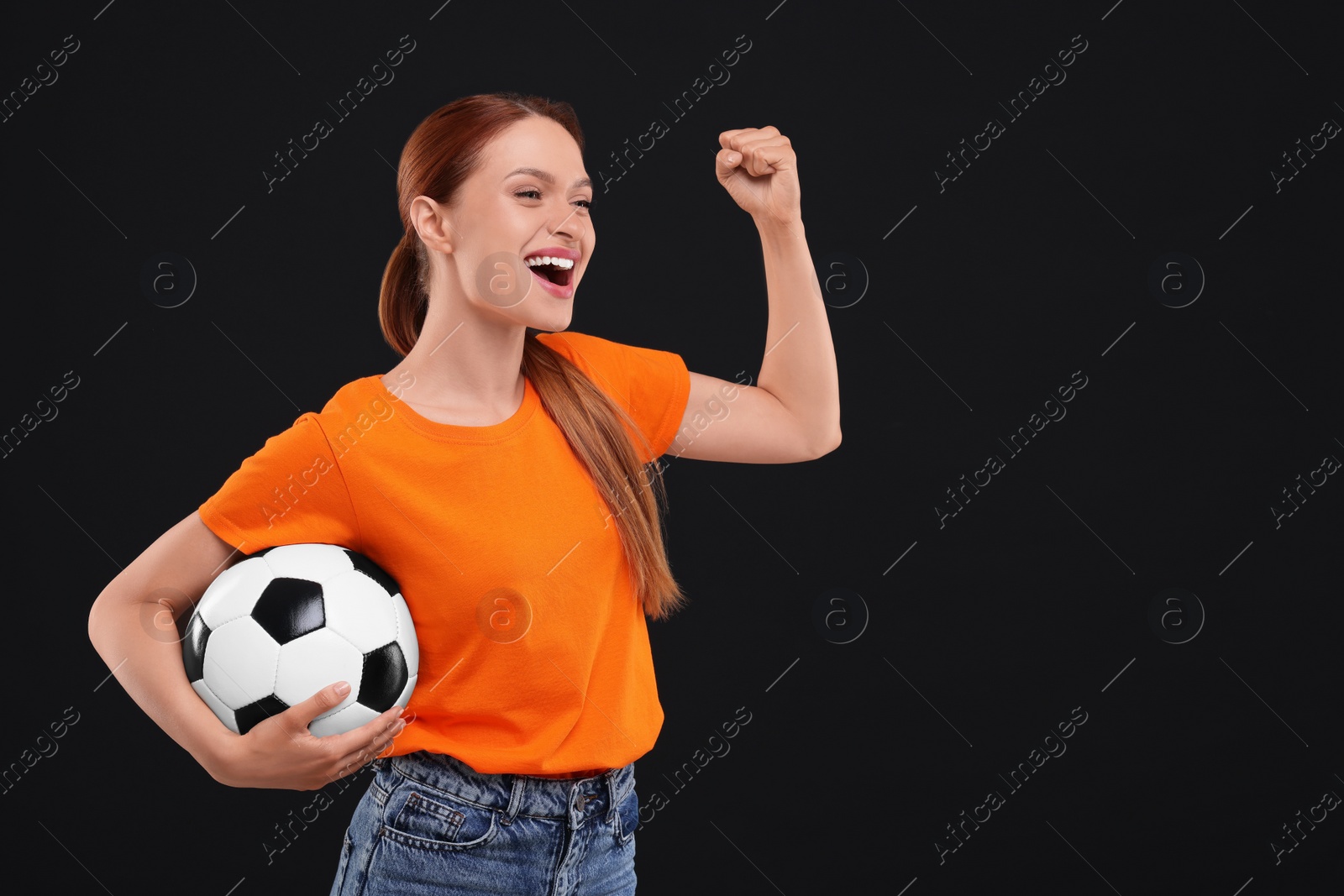 Photo of Happy fan with football ball on black background, space for text