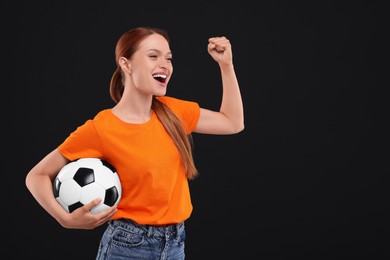 Photo of Happy fan with football ball on black background, space for text