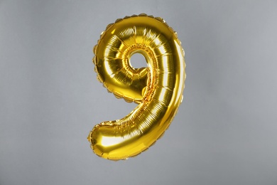 Golden number nine balloon on grey background