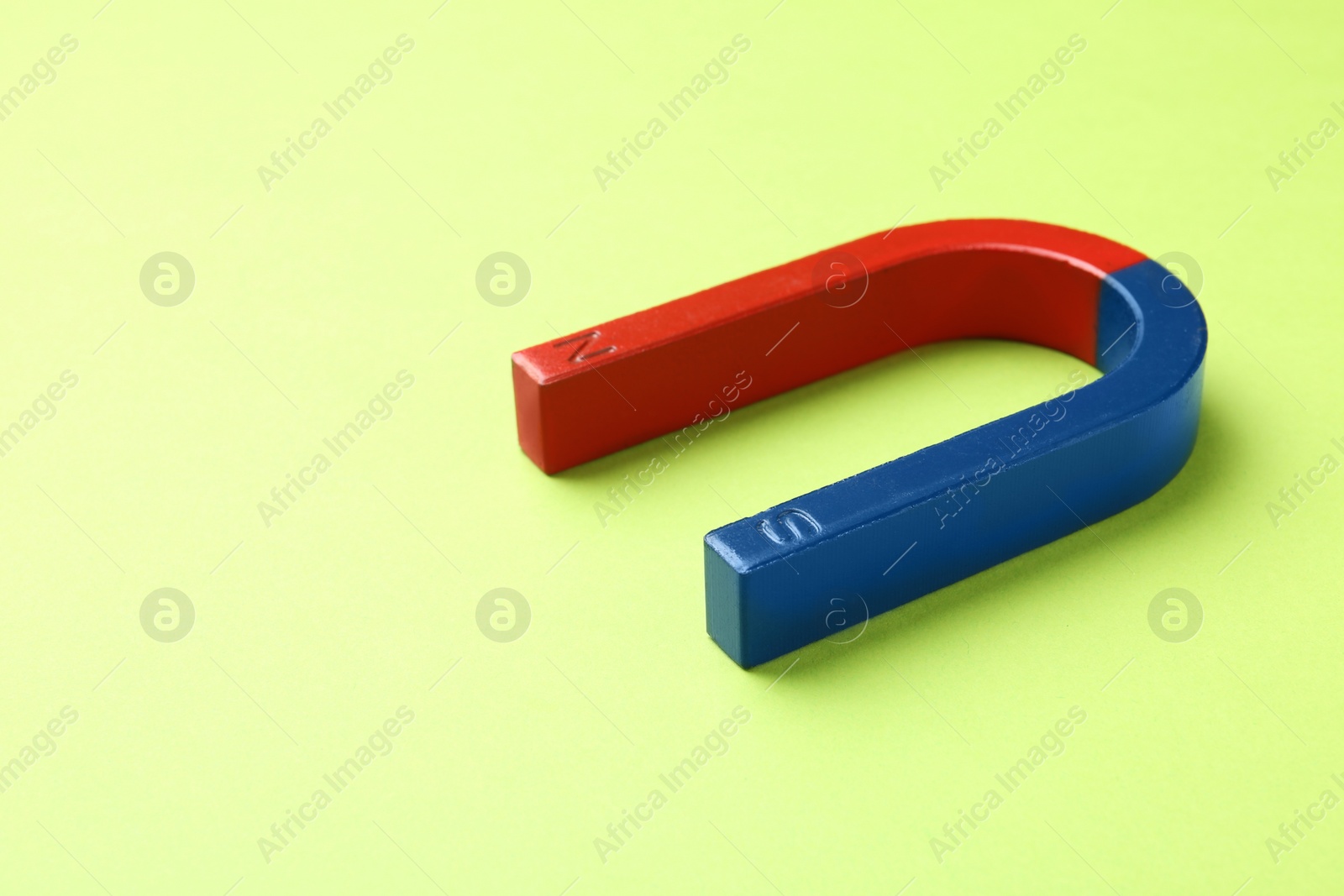 Photo of Red and blue horseshoe magnet on color background. Space for text