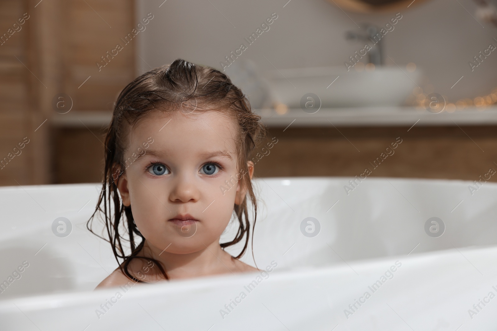 Photo of Cute little girl washing hair with shampoo in bathroom. Space for text