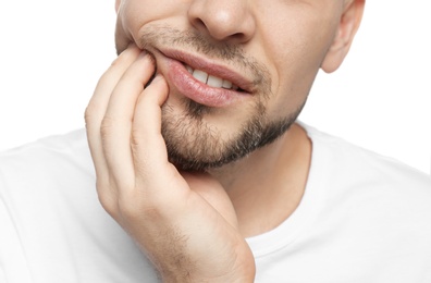 Young man suffering from toothache on white background