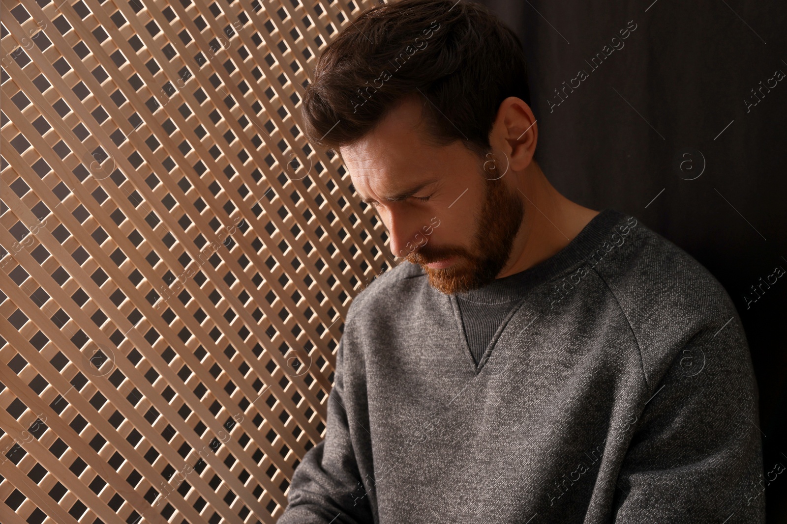 Photo of Upset man listening to priest during confession in booth, space for text