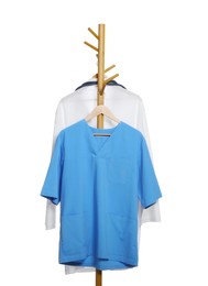 Photo of Light blue medical uniform and doctor's gown on rack against white background