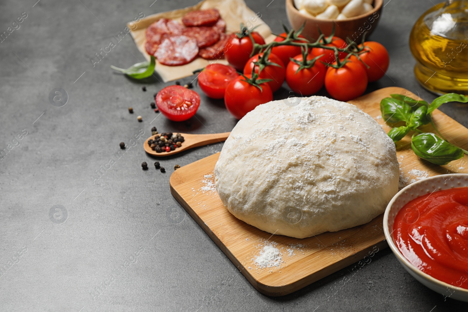 Photo of Dough and fresh ingredients for pepperoni pizza on grey table