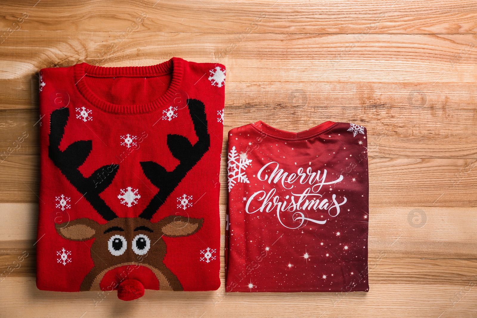 Photo of Folded warm Christmas sweaters on wooden table, flat lay