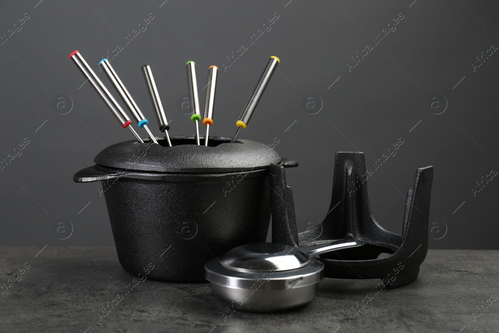 Photo of Fondue set on grey textured table. Kitchen equipment