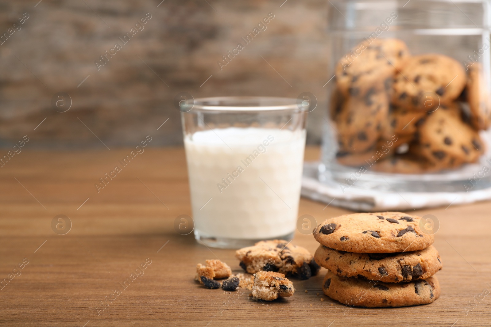 Photo of Tasty cookies with chocolate chips and glass of milk on wooden table