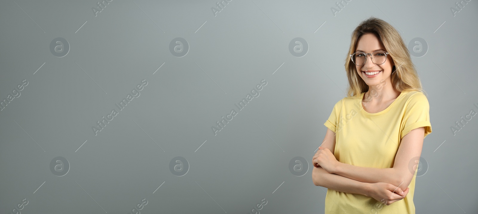 Photo of Portrait of happy young woman with beautiful blonde hair and charming smile on grey background. Space for text