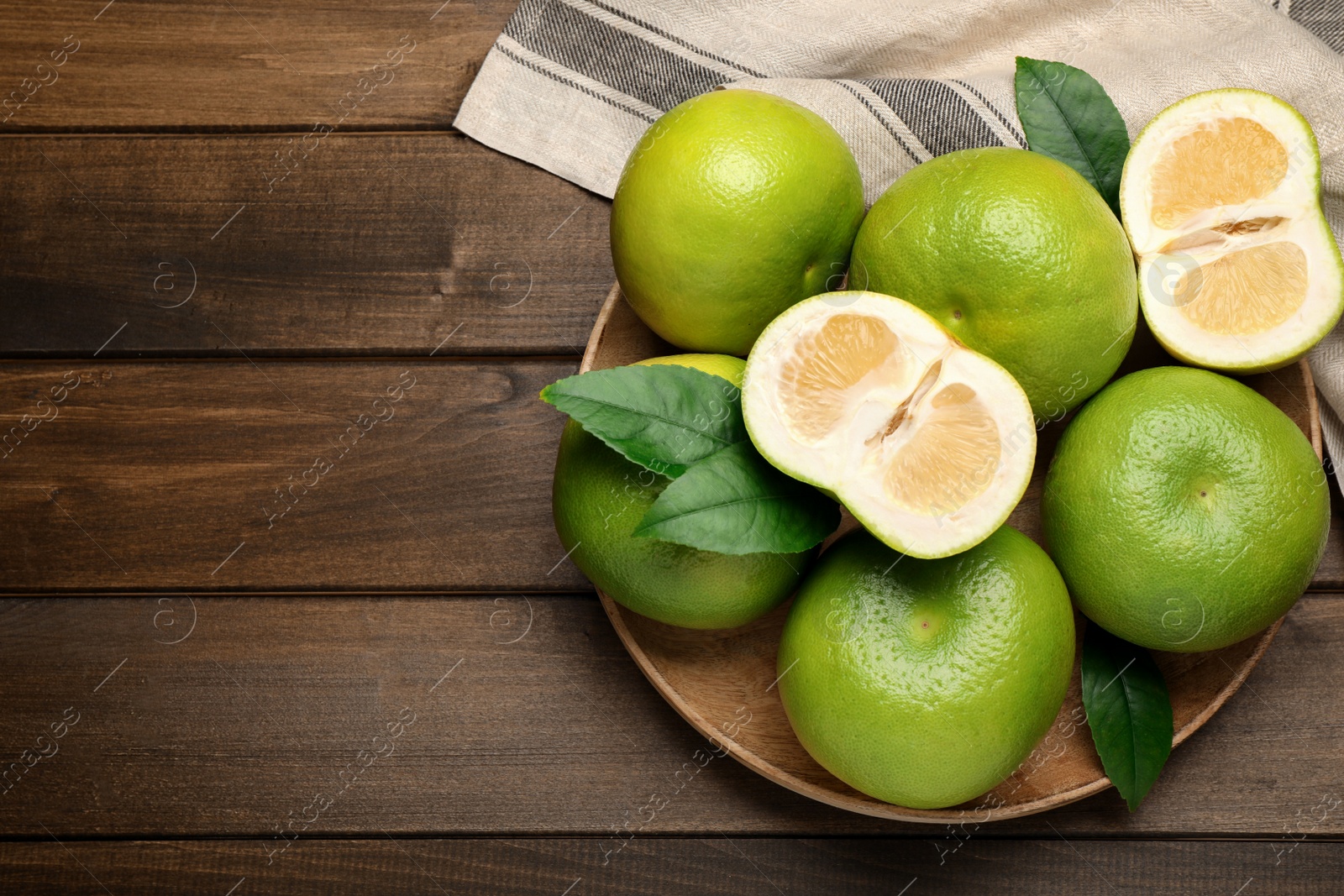 Photo of Whole and cut sweetie fruits on wooden table, flat lay. Space for text