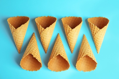 Empty wafer ice cream cones on blue background, flat lay