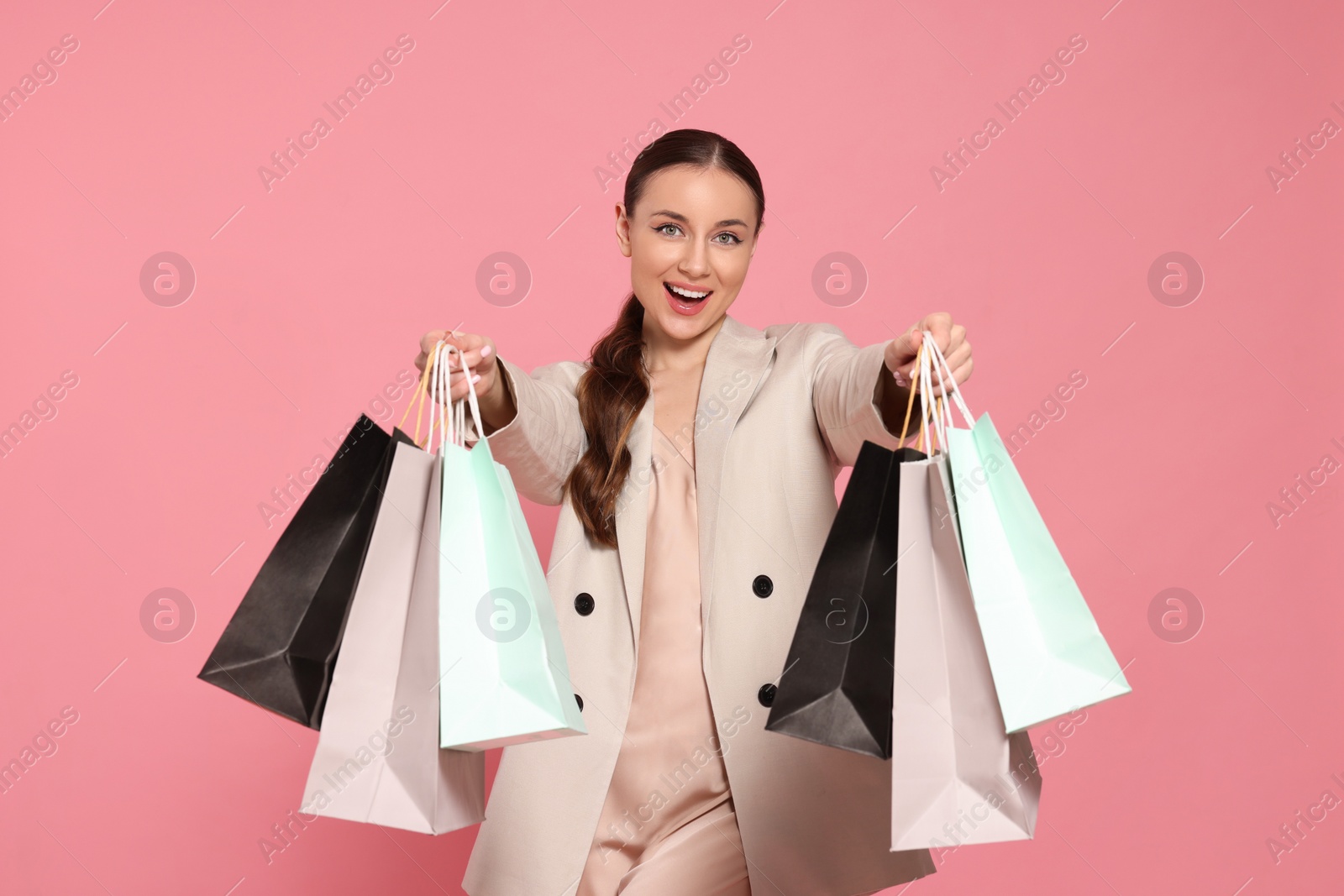 Photo of Stylish young woman with shopping bags on pink background