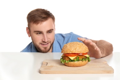 Photo of Young man and tasty burger on white background
