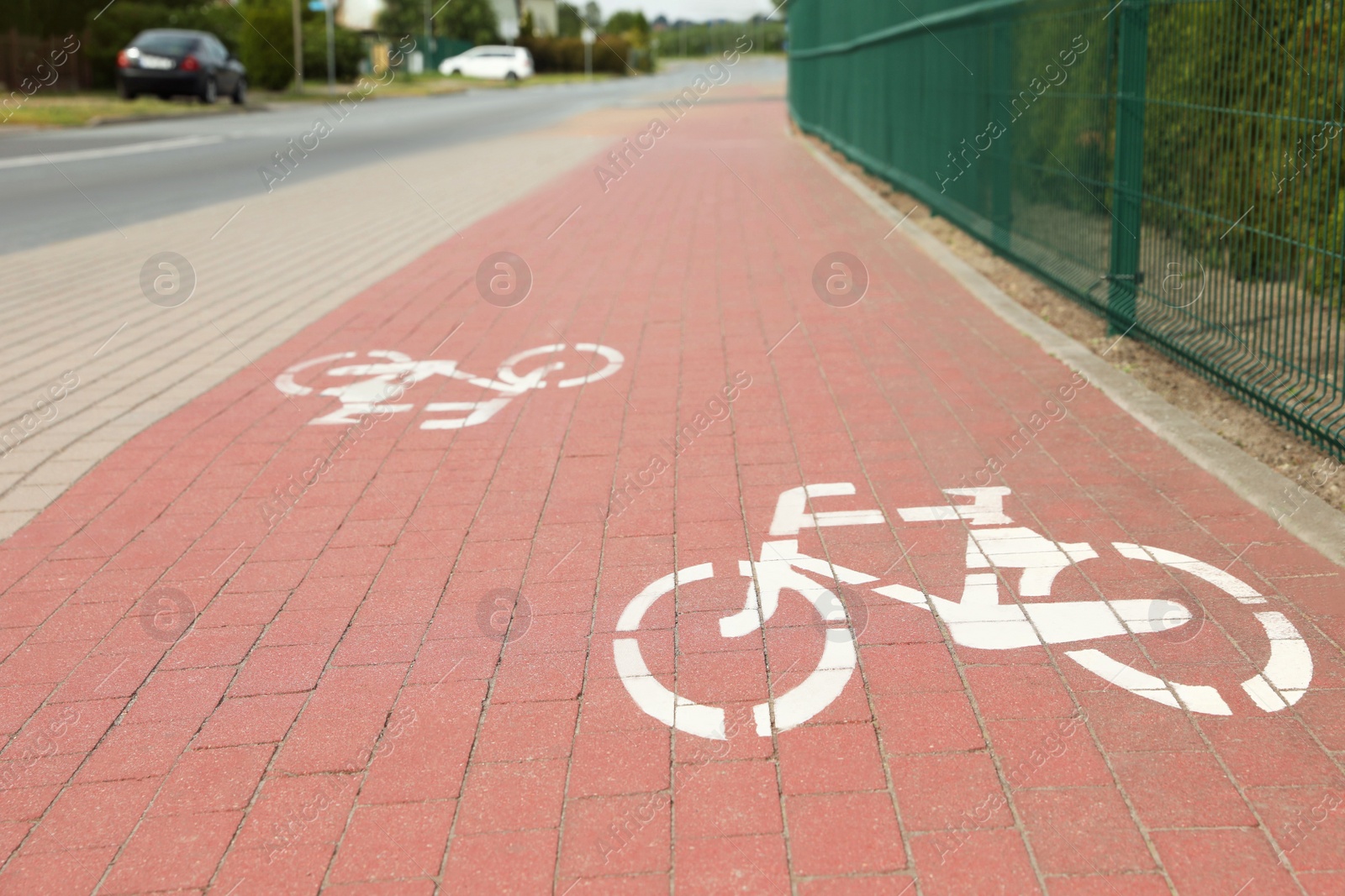 Photo of Red bicycle lane with white signs on pavement along road