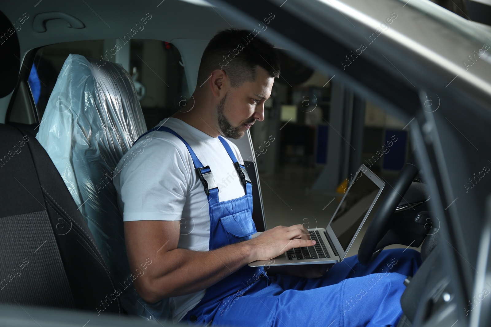 Photo of Mechanic with laptop doing car diagnostic at automobile repair shop