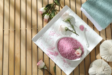 Flat lay composition with pink sea salt on wooden table, space for text
