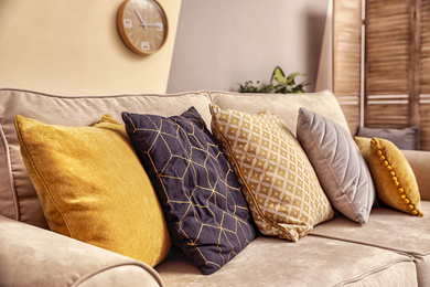 Pillows on modern sofa indoors, closeup. Stylish room interior decor