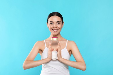 Photo of Young woman with bottle of micellar water on light blue background