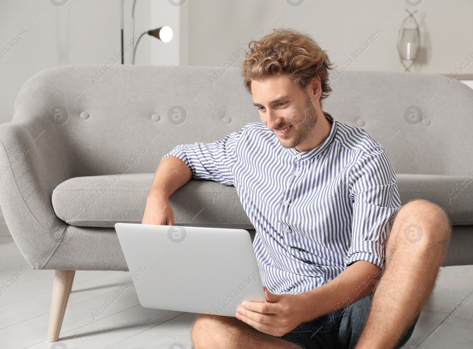 Photo of Young man with laptop sitting on floor at home