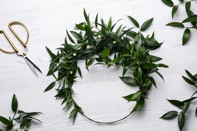 Photo of Unfinished mistletoe wreath and florist supplies on white wooden table, flat lay. Traditional Christmas decor