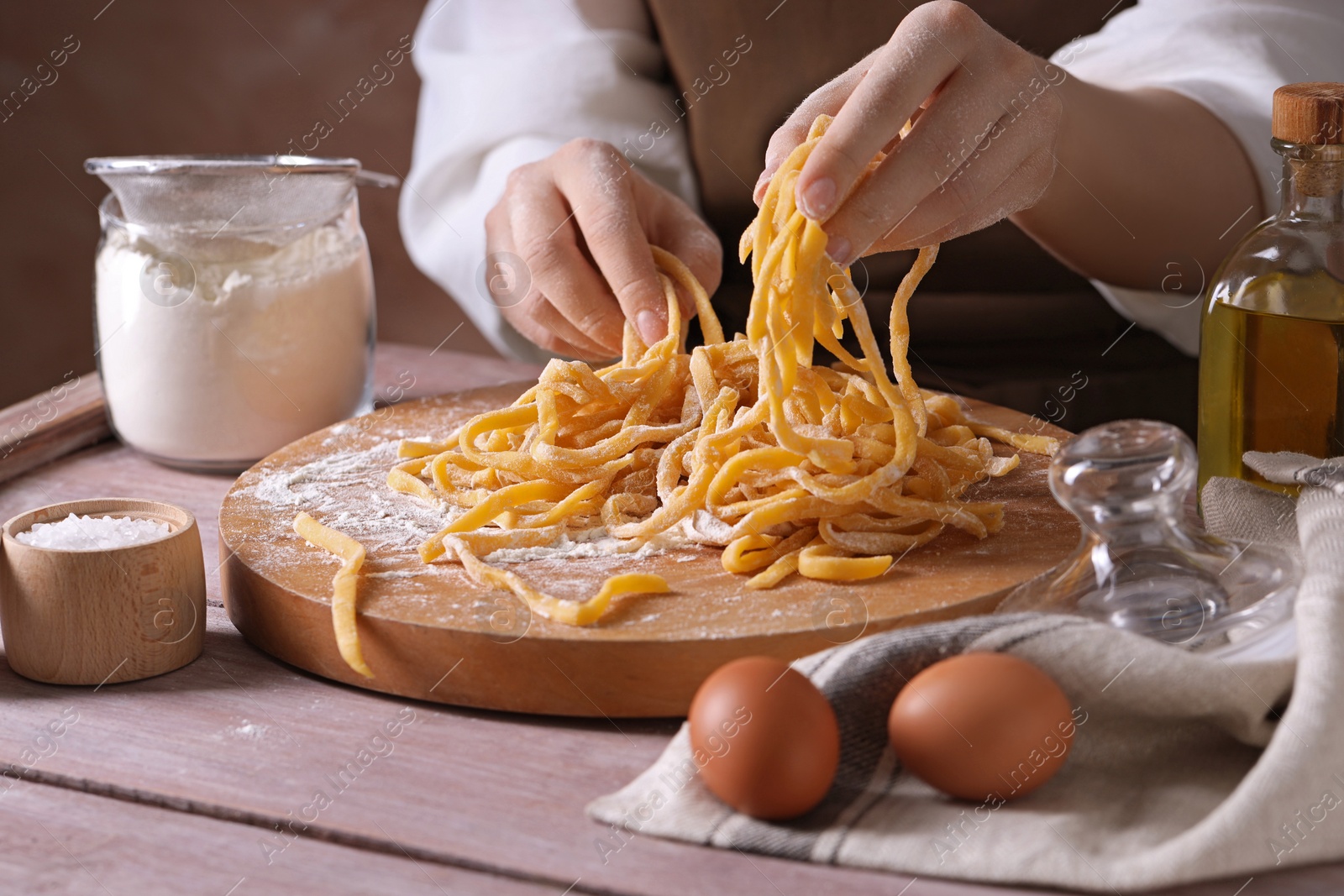 Photo of Woman making homemade pasta at wooden table, closeup