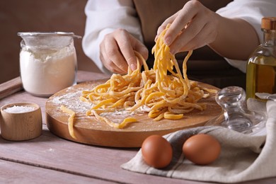 Photo of Woman making homemade pasta at wooden table, closeup