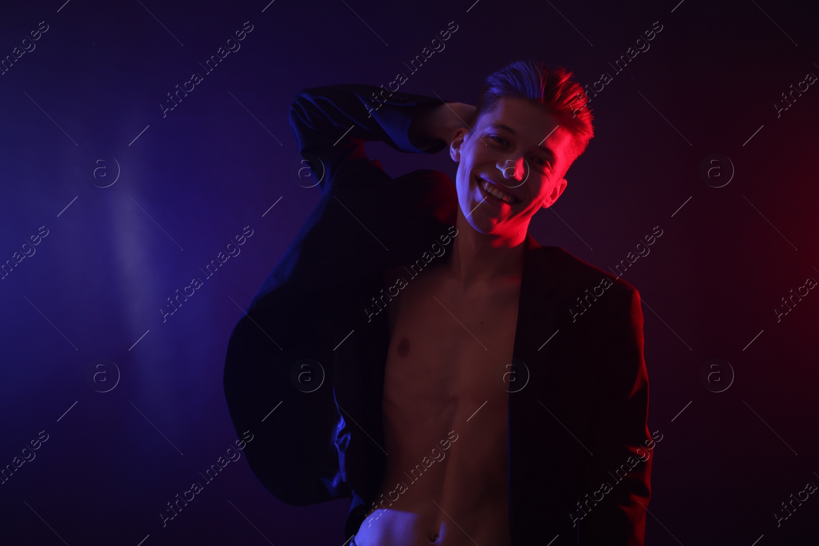 Photo of Sexy young man on dark background in neon lights