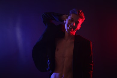 Sexy young man on dark background in neon lights