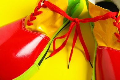 Photo of Pair of clown's shoes on yellow background, closeup