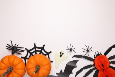 Photo of Flat lay composition with pumpkins and spiders on white background, space for text. Halloween celebration