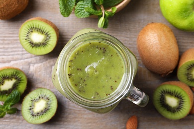 Delicious kiwi smoothie and fresh fruits on wooden table, flat lay