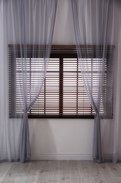 Photo of Window with beautiful curtains and blinds in empty room