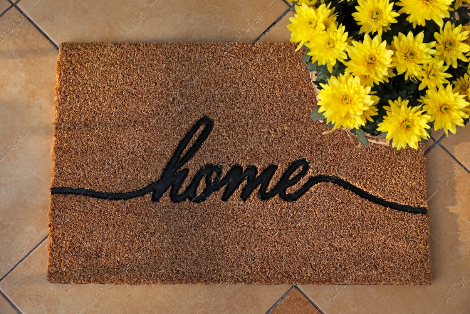 Photo of Doormat with word Home and flowers on tiled floor, flat lay