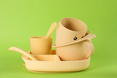Photo of Set of plastic dishware on light green background. Serving baby food