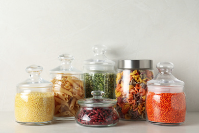 Photo of Glass jars with different types of groats on white wooden table