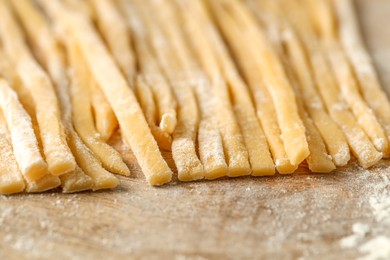 Photo of Raw homemade pasta and flour on wooden table, closeup