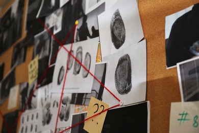 Photo of Detective board with crime scene photos, stickers, clues and red thread, closeup