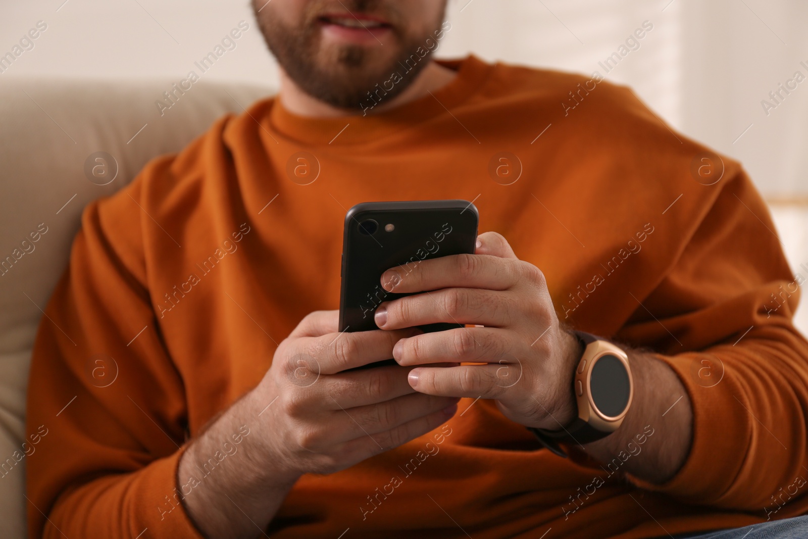 Photo of Young man with smart watch and phone at home, closeup