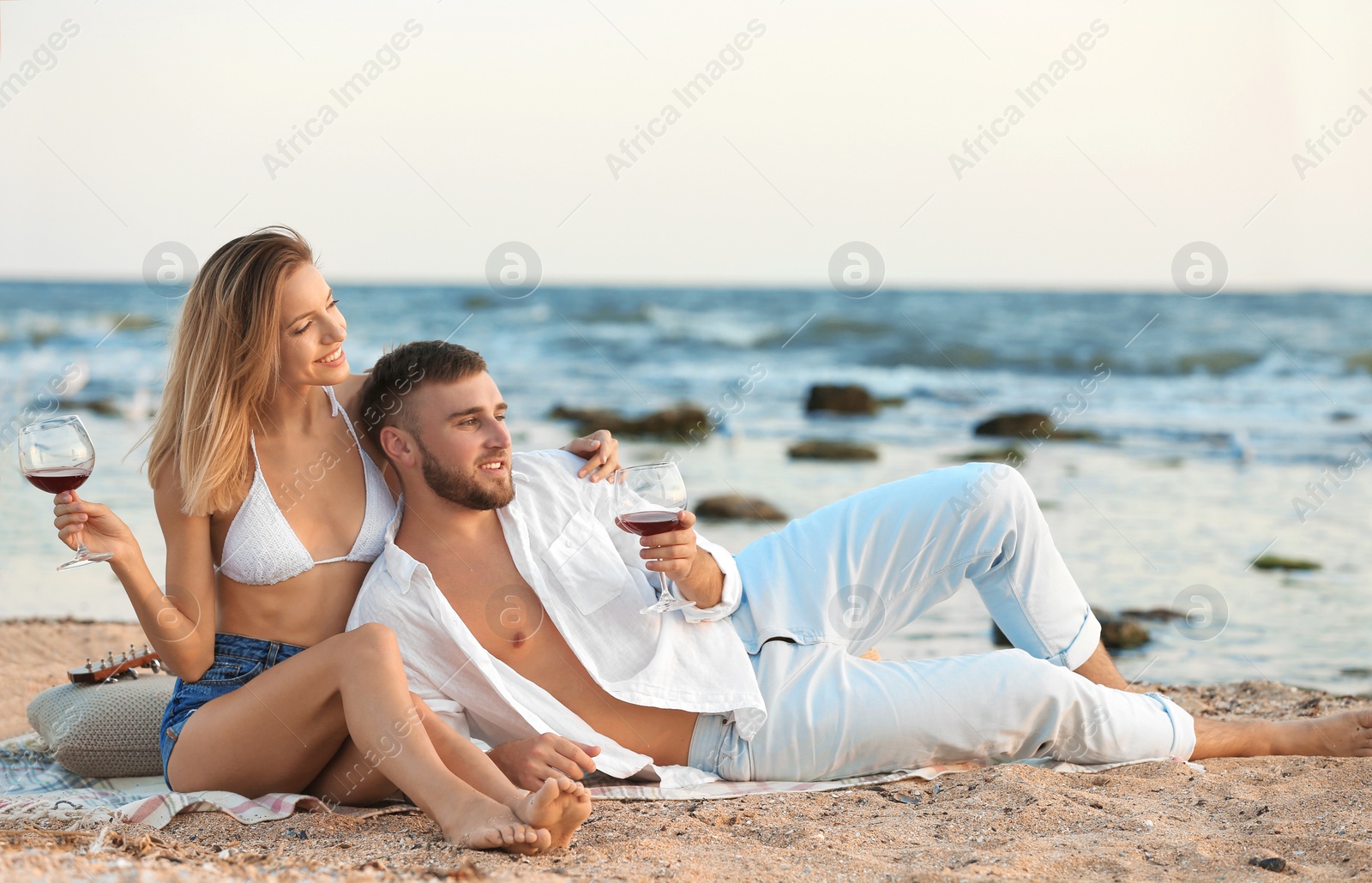 Photo of Young couple with glasses of wine on beach