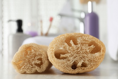 Photo of Natural loofah sponges on table in bathroom, closeup