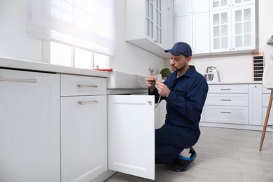 Photo of Professional plumber fixing water tap in kitchen