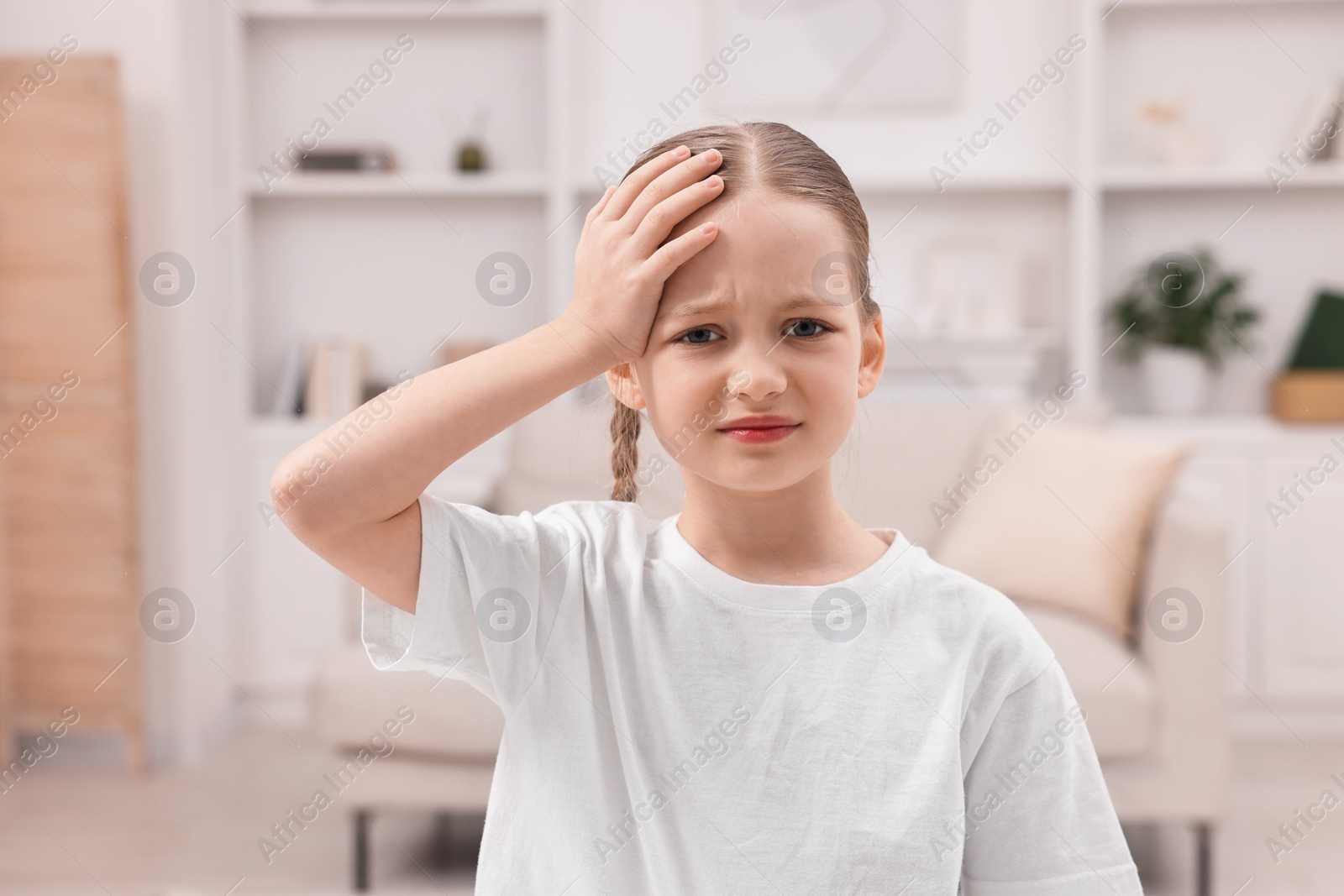 Photo of Little girl suffering from headache at home