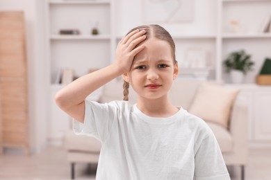 Photo of Little girl suffering from headache at home