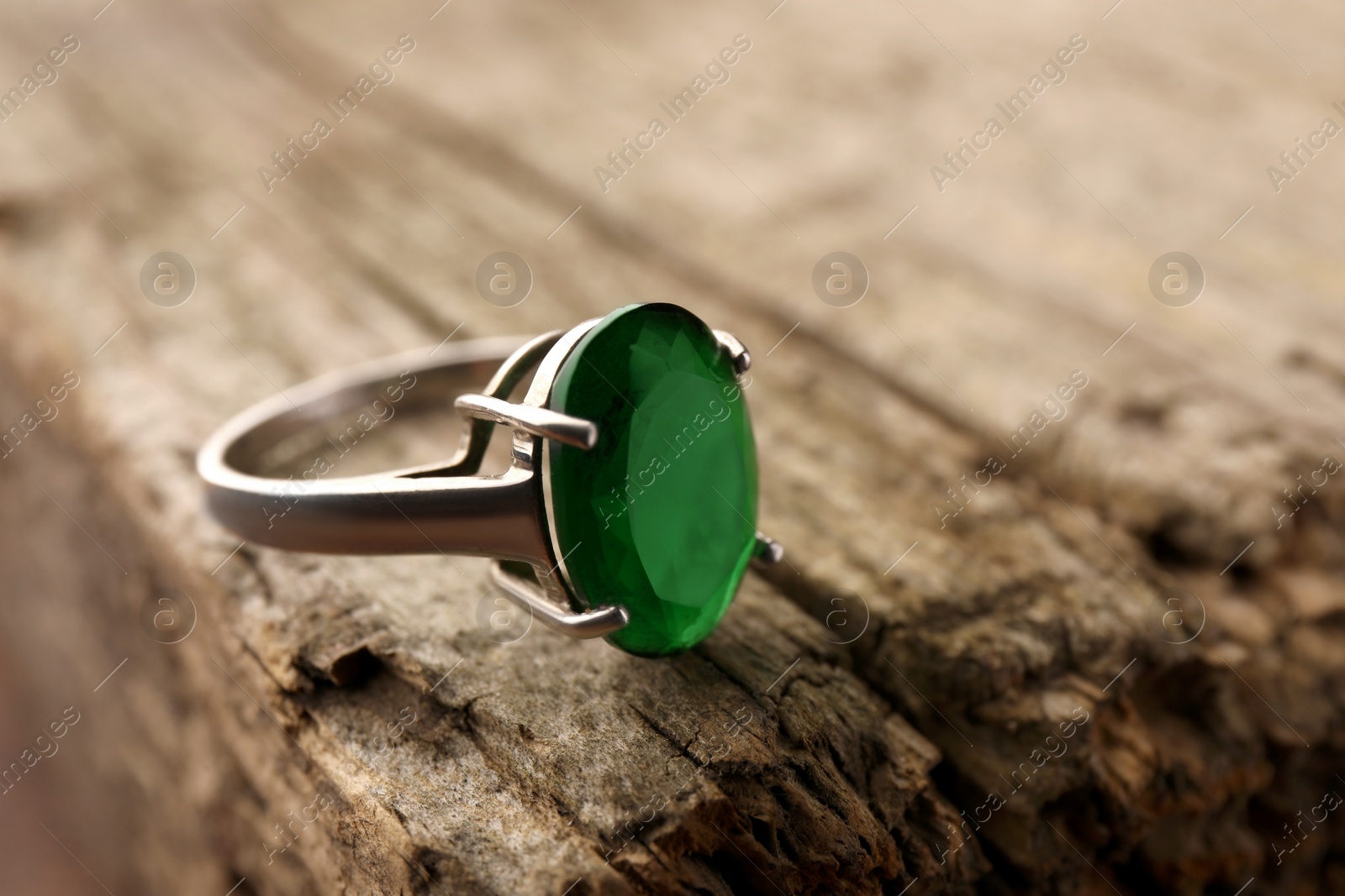 Photo of Beautiful ring with gemstone on wooden surface, closeup. Space for text