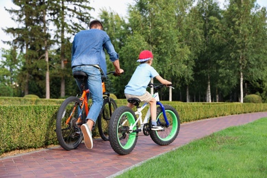 Photo of Dad and son riding modern bicycles outdoors