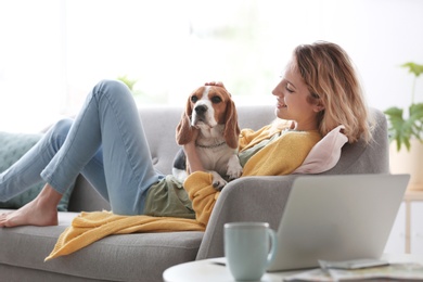 Photo of Young woman with her dog on sofa at home